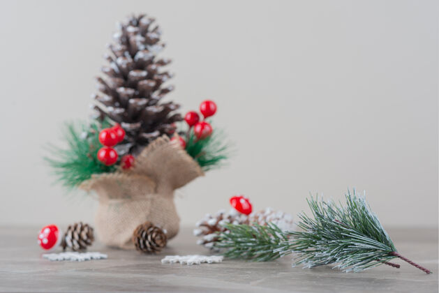 树枝用冬青浆果和树枝装饰的松果放在大理石桌上松树圣诞圆锥形