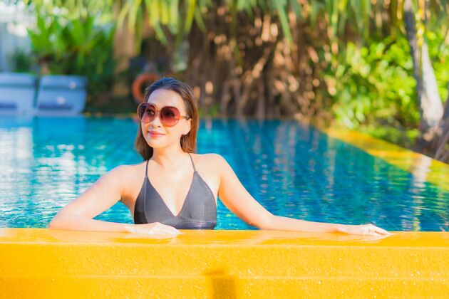 水疗肖像美丽的亚洲年轻女子放松微笑休闲围绕室外游泳池近海阳光女性酒店