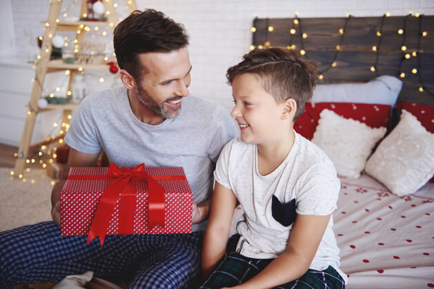 抱着带着圣诞礼物的父子俩盒子儿子分享