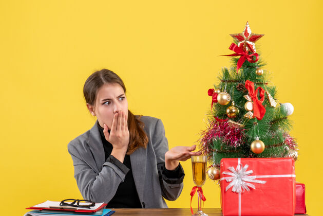 鸡尾酒前视图漫步女孩坐在圣诞树和礼物鸡尾酒桌边电脑导演人