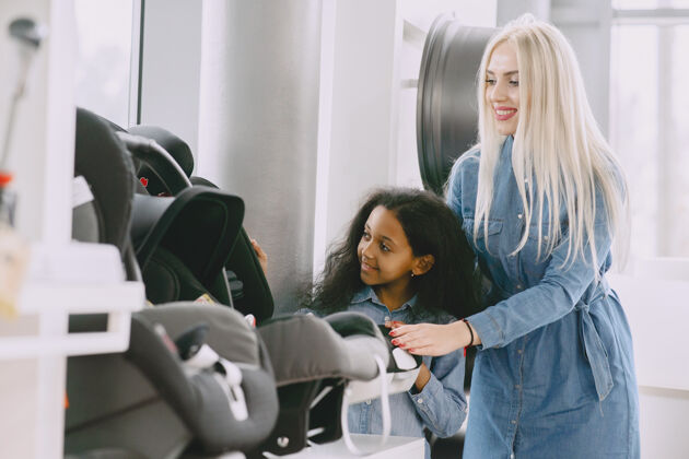 女性一家人在汽车沙龙里一个女人在买汽车座椅一个非洲小女孩和妈妈在一起女儿美国国际