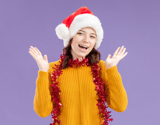 周围快乐的年轻斯拉夫女孩戴着圣诞帽 脖子上戴着花环 举手站在紫色背景上 留有复制空间升起脖子帽子
