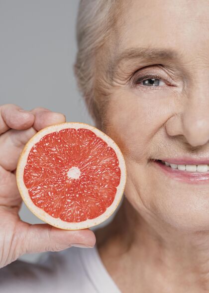 美丽特写笑脸女人拿着红橙子护理女人老年人