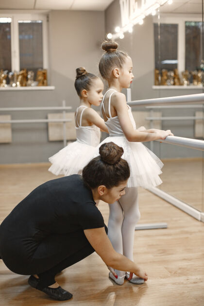 锻炼穿着粉色芭蕾舞服的可爱的小芭蕾舞演员穿着尖头鞋的孩子们在房间里跳舞孩子们和老师一起上舞蹈课姿势团体女性