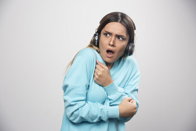年轻穿着蓝色运动衫的金发女孩听着耳机 却不喜欢音乐听人休闲