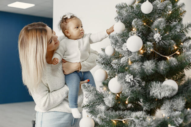 美国人们在为圣诞节做准备母亲在和女儿玩耍一家人在节日的房间里休息孩子穿着毛衣孩子小花环