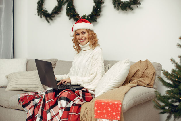 圣诞老人房间里的女人穿白毛衣的金发女人拿着笔记本电脑的女人圣诞节盒子肖像