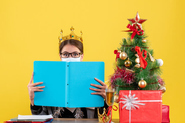 季节正面图年轻女孩戴着王冠 脸上覆盖着蓝色的纸夹圣诞树和鸡尾酒礼物文件夹皇冠蓝色