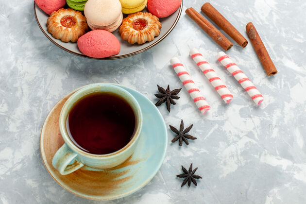 生的俯瞰美味的法国马卡龙饼干肉桂和茶在浅白的桌子上烤蛋糕饼干糖甜的照片顶部咖啡烘焙
