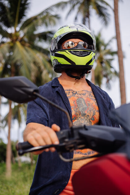 乘坐在热带丛林的田野上纹着红色摩托车的壮自由运动