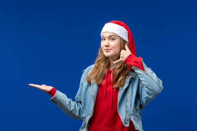 灯光正面图：年轻女性戴着红色圣诞帽 背景为淡蓝色的圣诞情感色彩帽子可爱蓝色