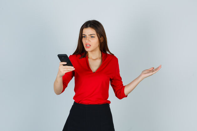 压力穿红衬衫 裙子的年轻女士看着手机人痛苦担心