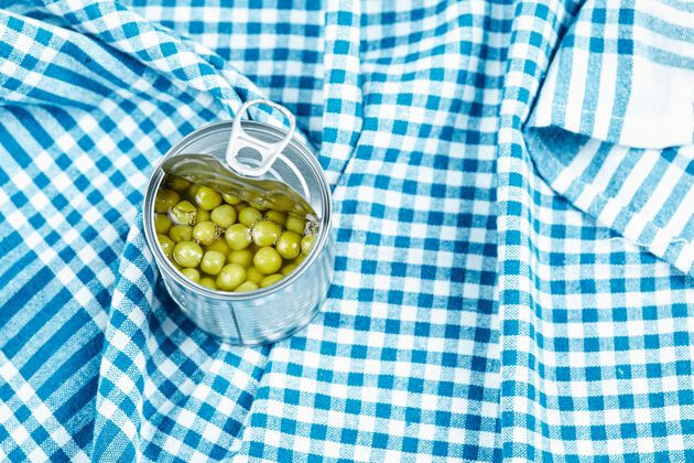 料理蓝色桌布上放着煮青豌豆的罐头闪亮小吃堆