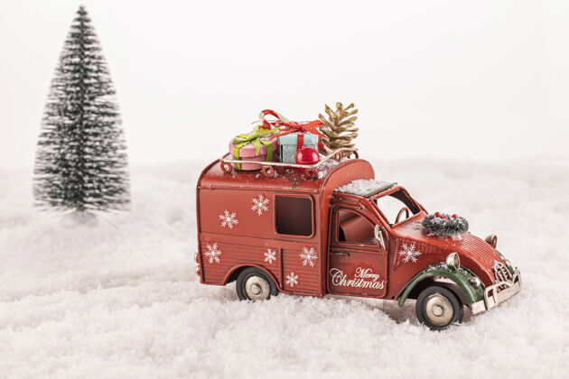 雪以圣诞树为背景 在人造雪上装饰有装饰品的小型汽车玩具乐趣礼物小