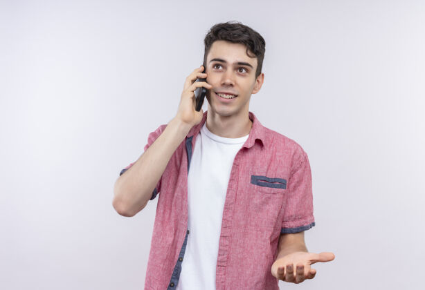 小伙子微笑的白人年轻人穿着粉色衬衫在孤立的白色背景下讲电话微笑白色电话