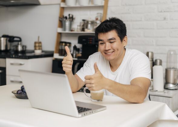 距离大流行期间 家里的男人在笔记本电脑上视频通话时竖起大拇指大拇指向上男人
