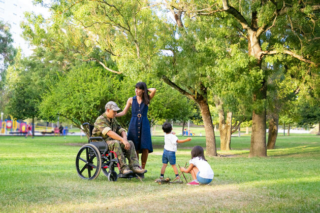 军队孩子们在户外为妈妈和轮椅上的残疾军人爸爸安排篝火残疾退伍军人或家庭户外概念母亲男人肖像