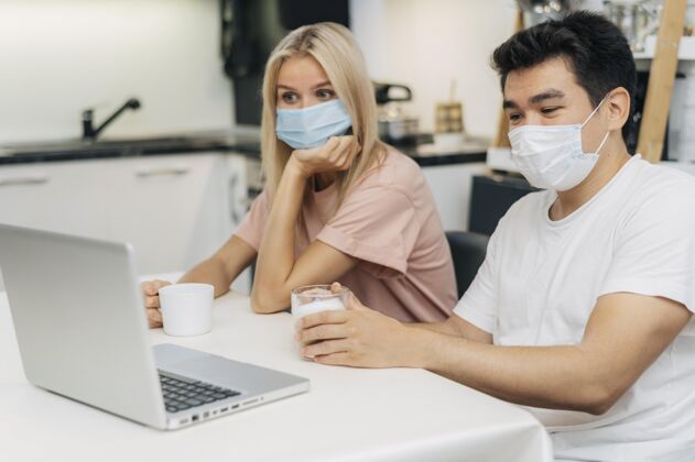 Covid19流感大流行期间 一对夫妇带着医用口罩在家里用笔记本电脑工作笔记本电脑男性大流行
