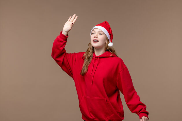 肖像前视图圣诞女孩挥手致意和问候棕色背景假日模型圣诞节视图问候脸