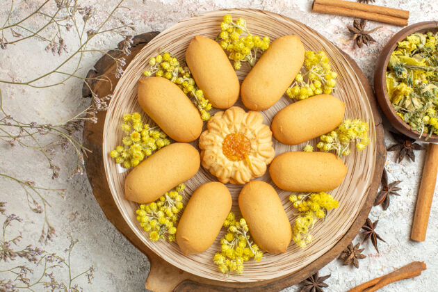 食品木盘上的饼干和白色大理石上的不同草药的特写镜头顶视图水果芒果