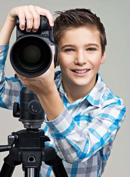 灰色三足动物上拿着相机的男孩在摄影棚摆姿势图片三脚架外观