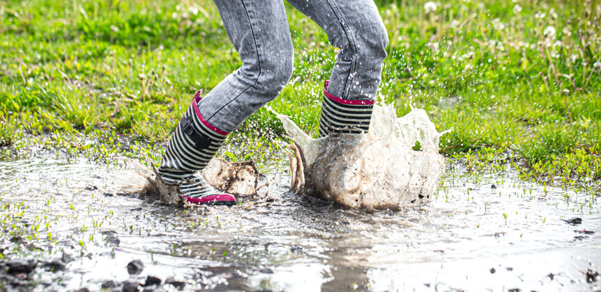 乡村胶靴在水坑里跳跃的过程中伴随着水花飞溅雨衣飞溅孩子