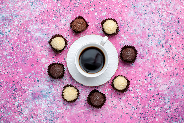 白俯瞰美味的巧克力糖果白色和黑巧克力 粉红色的桌子上放着一杯茶科技甜音乐