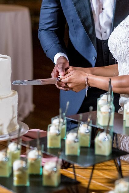 女性新娘和新郎正在切漂亮的白色结婚蛋糕已婚蛋糕仪式