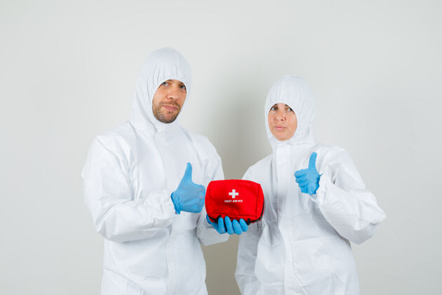 病毒两个医生拿着急救箱 穿着防护服竖起大拇指站成人防护