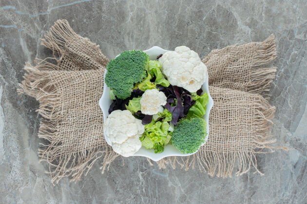 素食一盘花椰菜和花椰菜放在一块布包裹的大理石底座上花椰菜顶部视图饮食