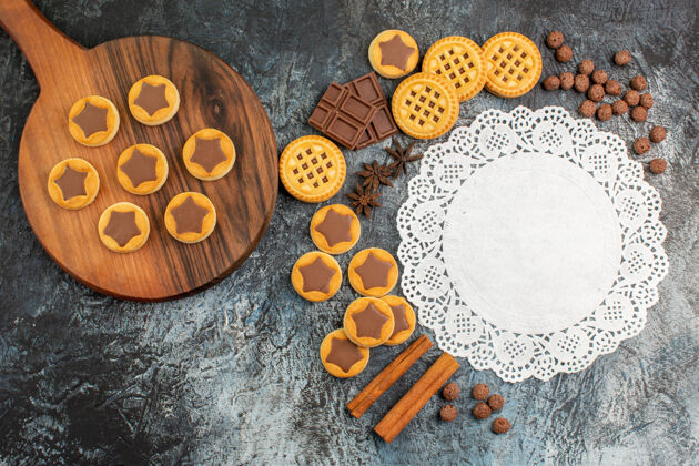 灰色木盘上饼干的俯视图 灰色地面上有许多糖果和一块白色蕾丝糖果饼干很多