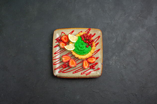 卡片顶视图美味的蛋糕与绿色奶油和草莓在黑暗的背景甜甜点茶扑克糖果赌场