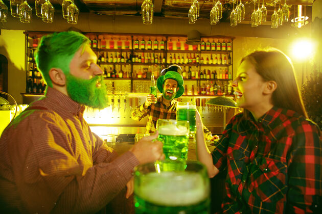 传统圣帕特里克节派对快乐的朋友在庆祝和喝绿色啤酒年轻男女戴着绿色帽子酒吧内部朋友爱尔兰微笑