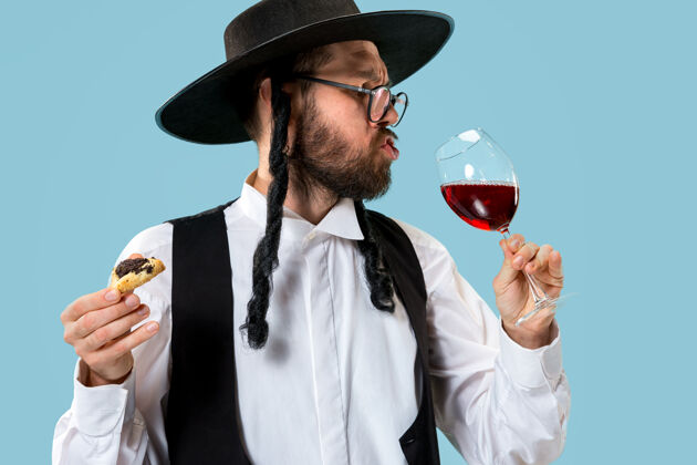 节日年轻的东正教犹太男子拿着哈曼塔森饼干过节葡萄酒男人庆祝