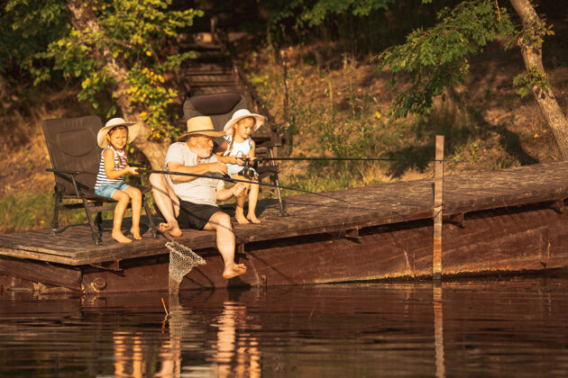 世代可爱的小女孩和他们的爷爷在湖边或河边钓鱼爱好钓鱼休息