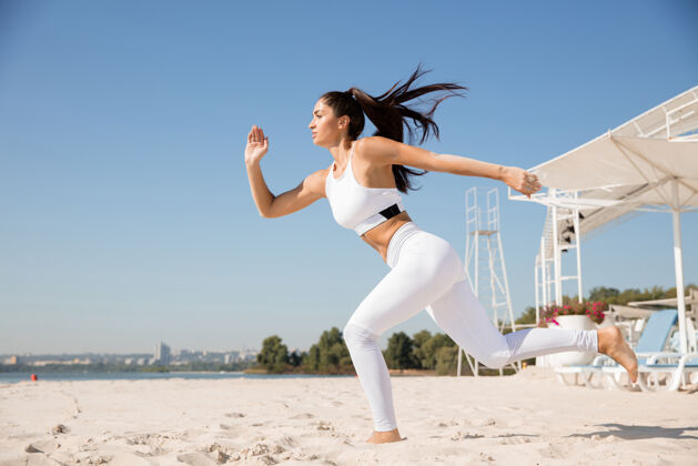 运动年轻健康的女人在沙滩上跑步和做弓箭步户外教练教练