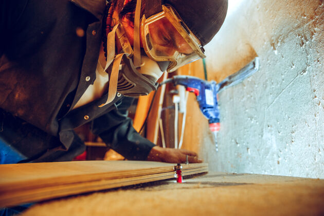 工人英俊的木匠在车间里用木溜冰鞋干活的画像专业木家