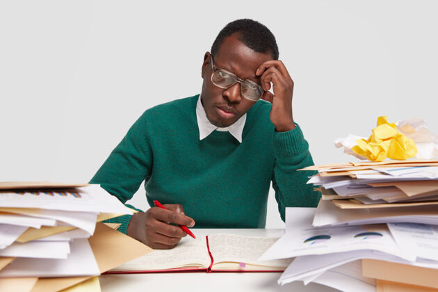 眼镜不高兴悲伤的美国黑人男职工有不满的表情 在工作场所工作疲劳 在记事本上写信息文件文书工作男性