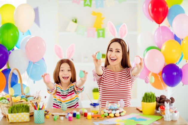 传统两个可爱的可爱的快乐的创意欢快的快乐的女孩的画像小的小的未成年的女儿戴着小兔子的耳朵在白色的光室内房间房子的棍子上展示装饰性的鸡蛋房子班级手工制作