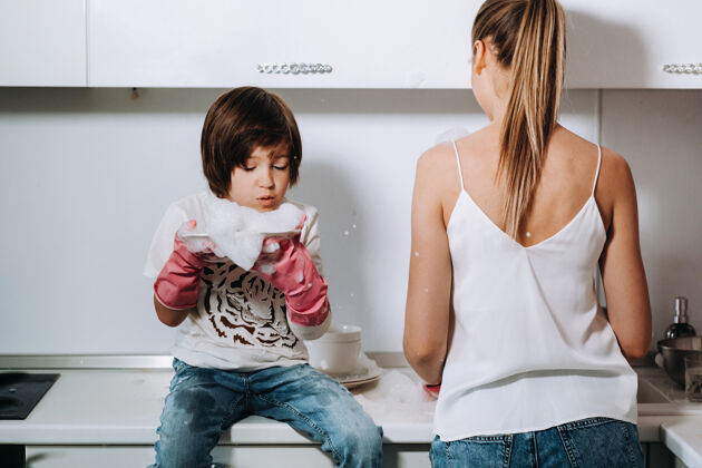 清洁戴着粉色手套的家庭主妇妈妈和儿子在洗手池里用洗衣粉洗手妻子家用孩子