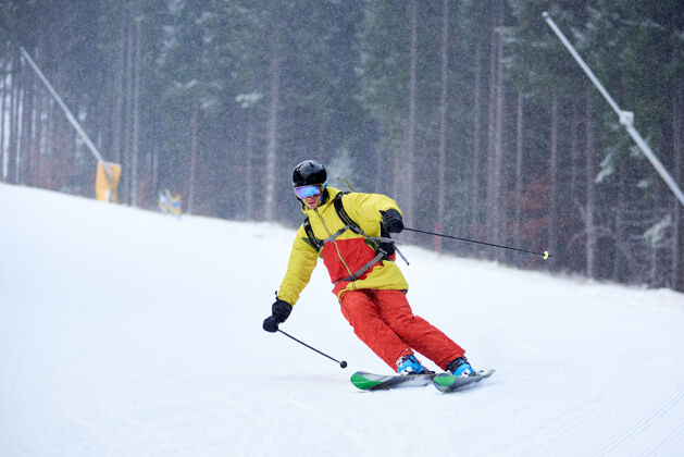 雕刻年轻男性滑雪者下山滑雪和在树木繁茂的山坡上做雕刻转弯的单一下降下雪时滑雪人假日旅行