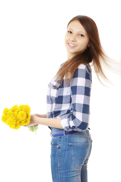 青少年穿着牛仔裤和格子衬衫的女孩 手里拿着黄色的野花白种人花俄罗斯