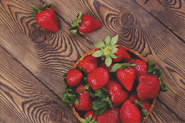 乡村一张棕色破旧的乡村木桌上 柳条碗里多汁草莓的俯视图素食生的盘子