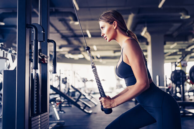 动作健身女人锻炼三头肌举重在健身房运动性感的女人在健身房用机器做运动信心健身房运动员