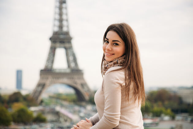 女人在埃菲尔铁塔的背景下 美丽的女孩向摄影师摆姿势秋天城市肖像围巾