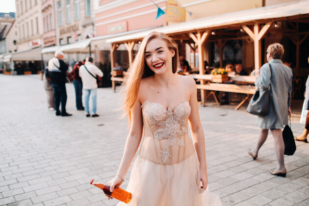运动弗罗茨瓦夫老城 一位穿着婚纱 留着长发 拿着酒瓶的新娘在一个古老的波兰中心拍摄婚纱照弗罗茨瓦夫市 波兰美丽姿势石头城