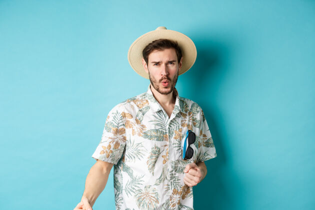 站快乐的游客穿着夏威夷衬衫 戴着夏天的帽子跳舞 享受假期的乐趣 站在蓝色的背景上胡须成人人