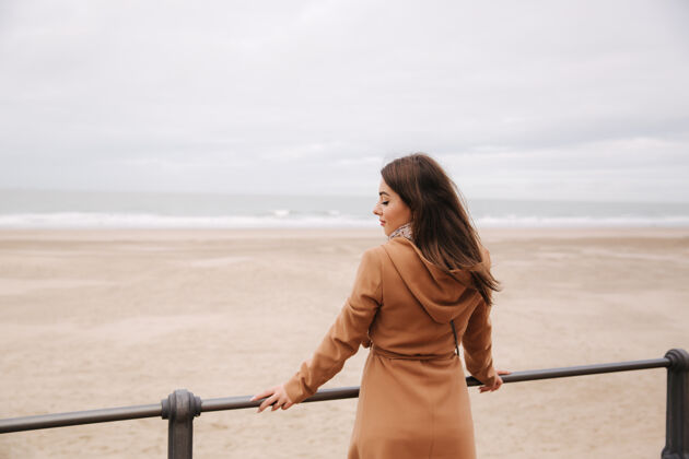 一一个穿着棕色外套的女人站在北海看海浪海洋海岸成人