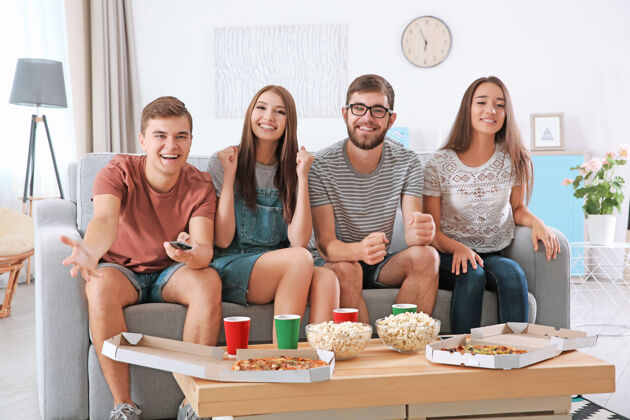 坐朋友们在家看电视爆米花比萨饼娱乐