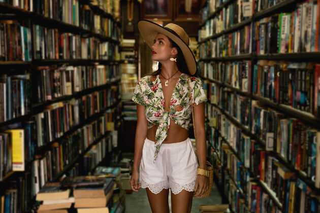 知识穿着时髦服装的漂亮女孩在老式小书店里寻找有趣的书使用许多老